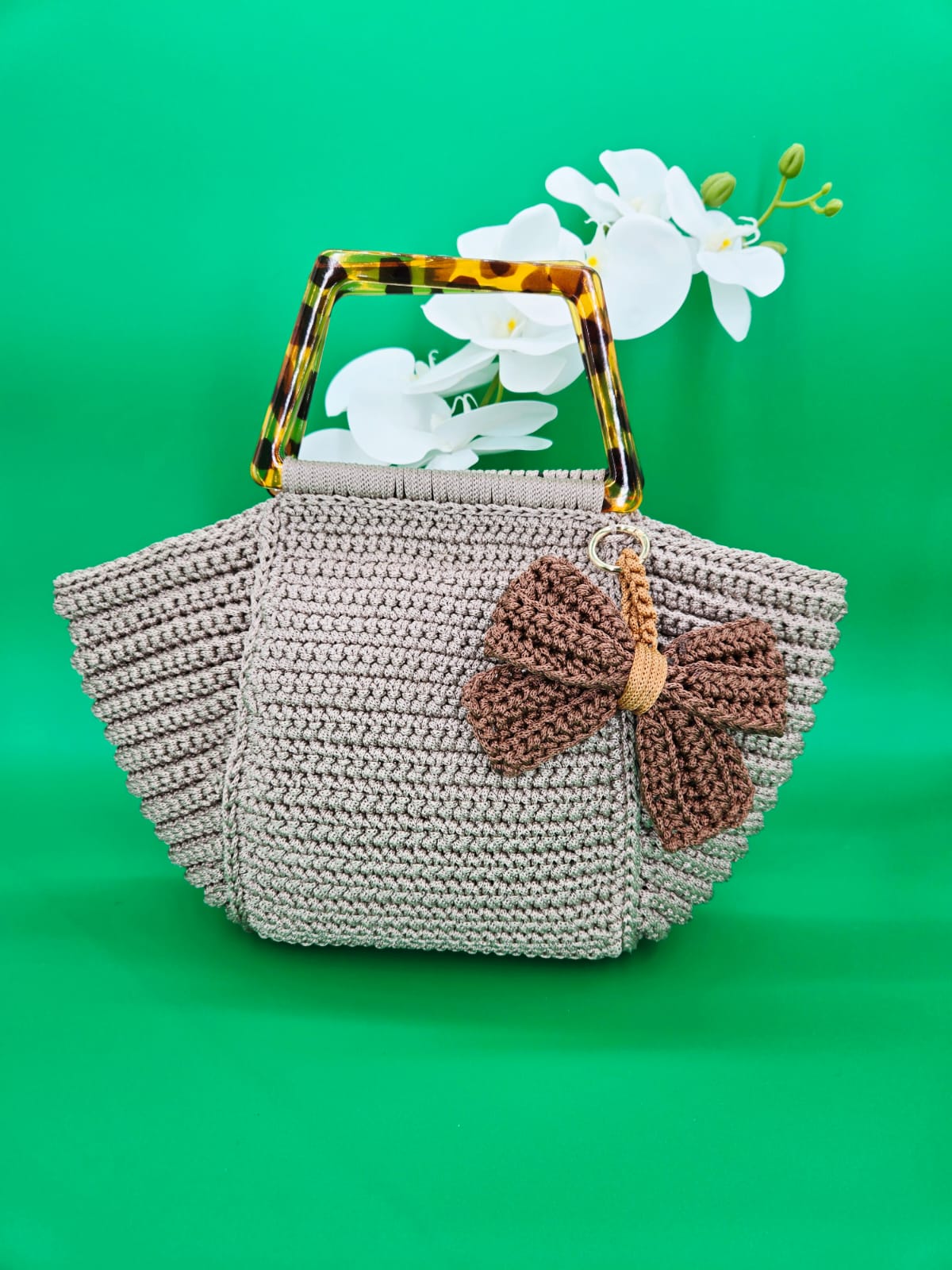 Bolso tejido a crochet con asas de carey y lazo decorativo